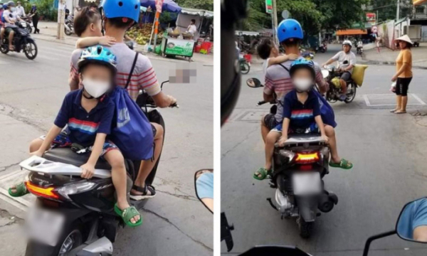 Ông bố trẻ một tay bế con một tay lái xe máy, phía sau còn cho con trai ngồi đối lưng vắt vẻo